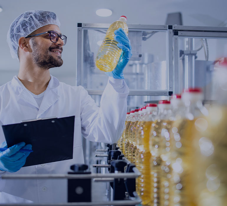 Un salariÃ© d'usine sur une ligne de production contrÃ´le des bouteilles d'huile