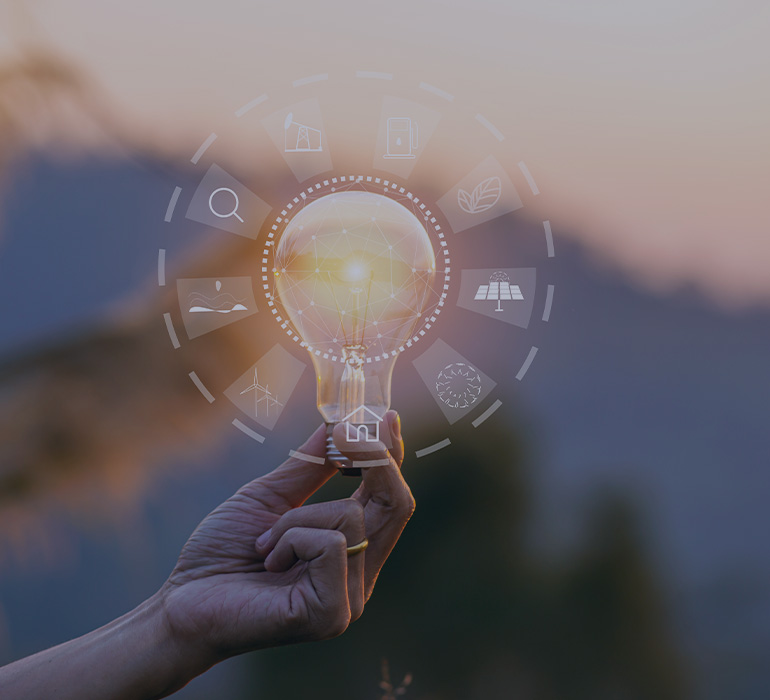 Main tenant une ampoule avec des pictogrammes reprÃ©sentant des sources d'Ã©nergie renouvelables