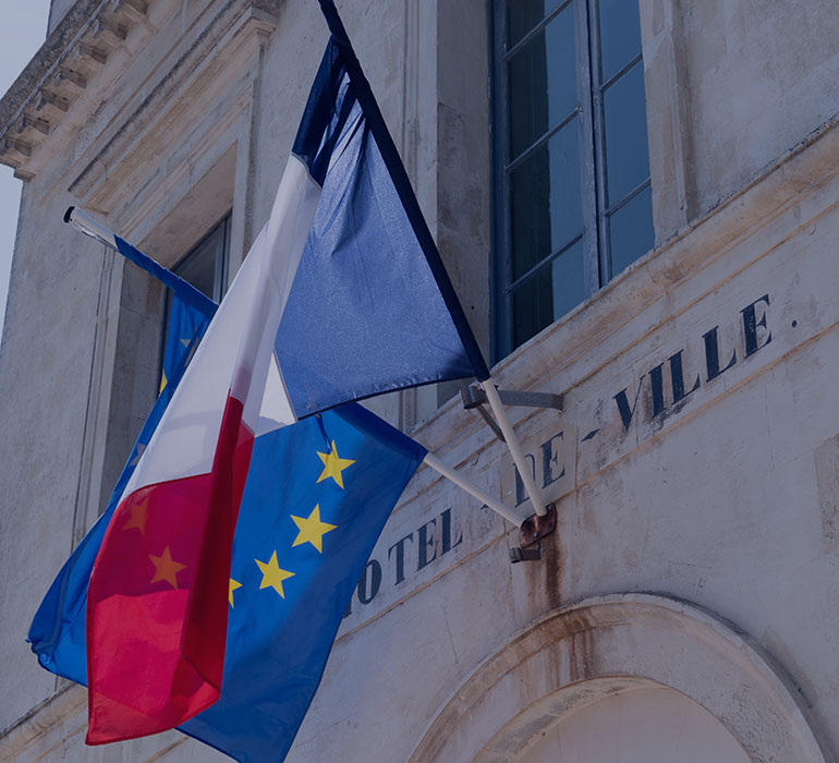 Un drapeau franÃ§ais et un drapeau europÃ©en sur le mur d'un hÃ´tel de ville