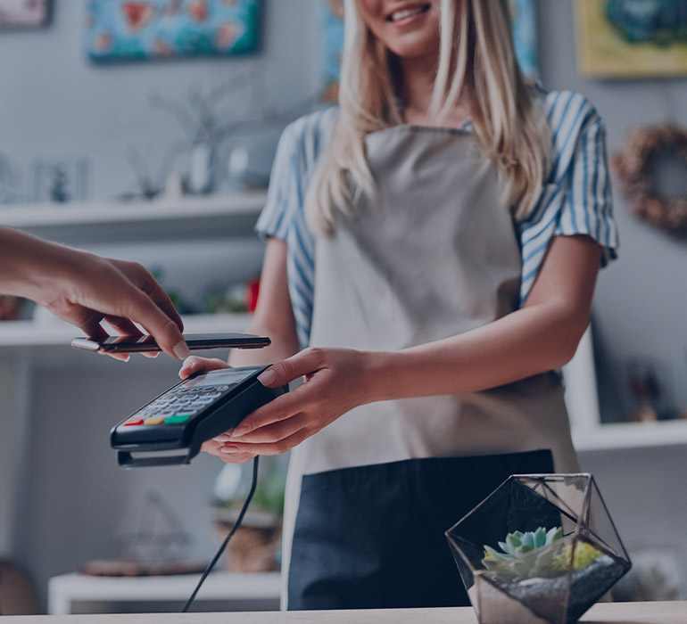 Une fleuriste tend un appareil bancaire Ã  son client